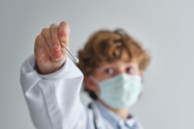 Boy doctor in sterile mask with cotton bud