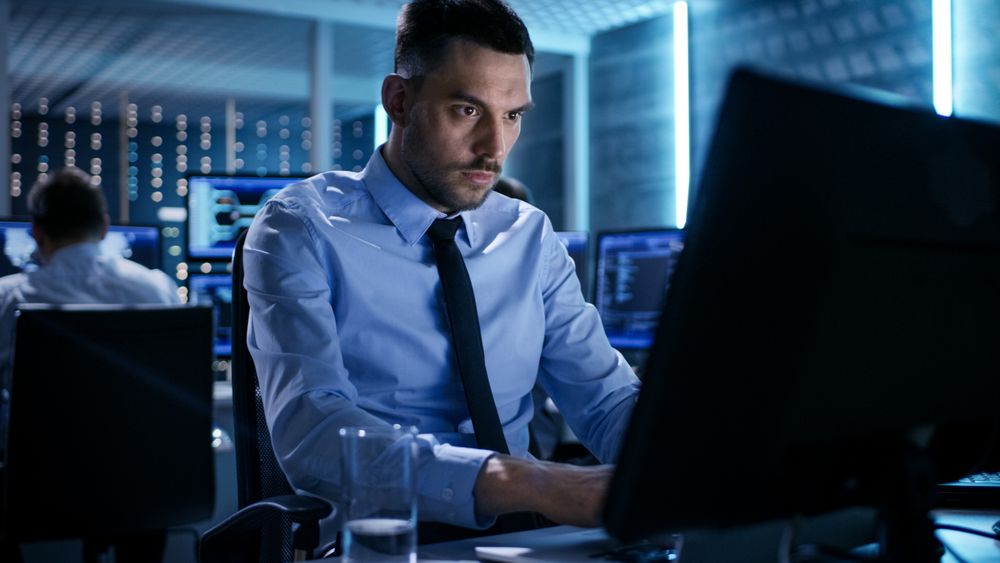 Close-up of Technical Engineer Working on His Computer With Multiple Displays in Monitoring Room.