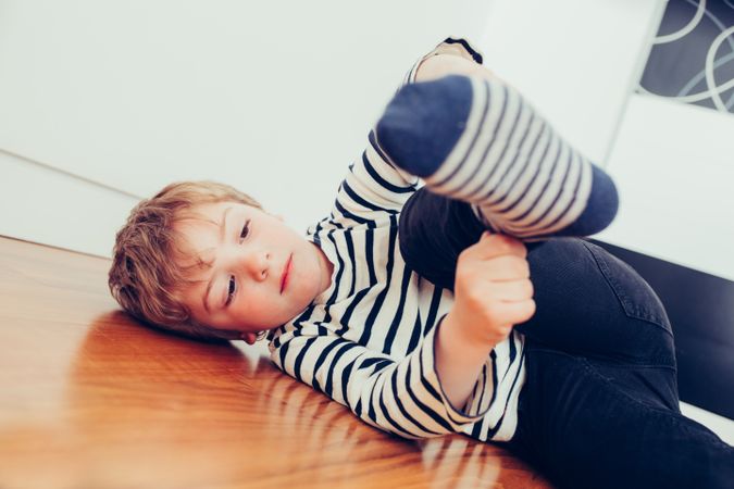 Cute blonde boy putting on his socks