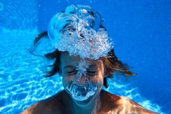 Funny preteen boy swimming in pool