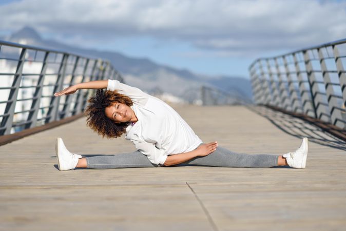Woman leaning to left side in splits on bridge with head resting on hands