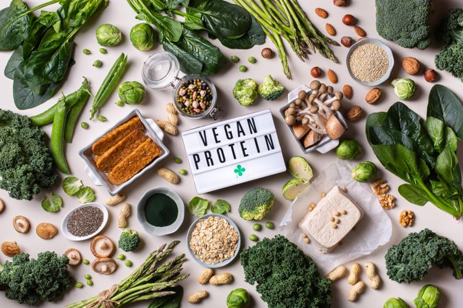 Variety of healthy vegan, plant based protein source and body building food with “Vegan” sign