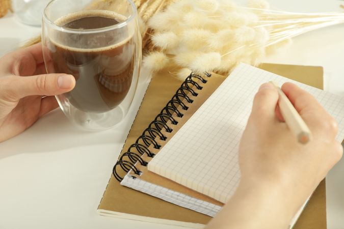 Woman writing in notebook with cup of coffee