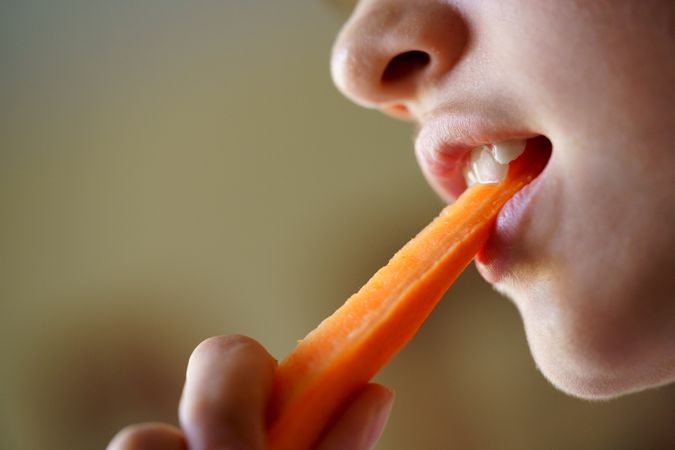 Girl biting into carrot stick