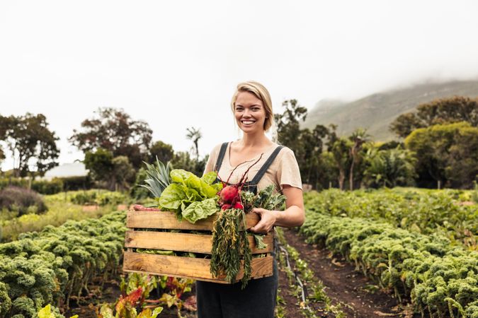 Young female organic farmer looking at the camera after harvesting fresh vegetables from her garden