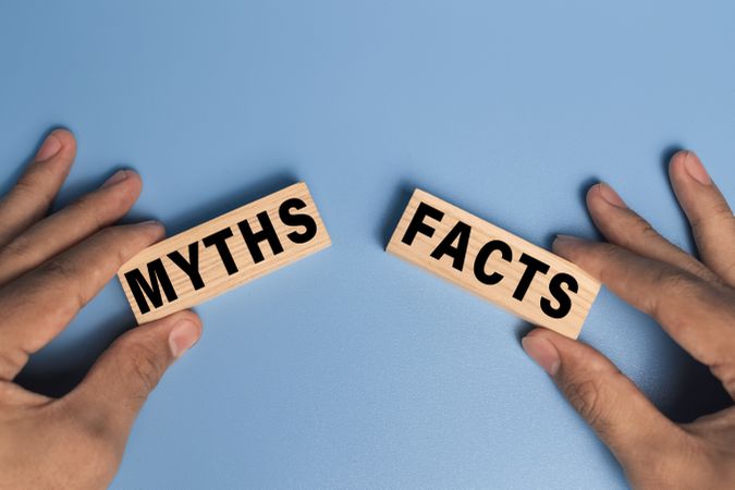 male hand holding myths and facts words text message on wooden blocks on blue background