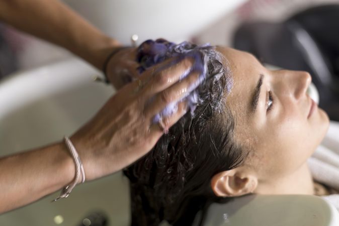 Female with head back in sink having shampoo massaged into her head