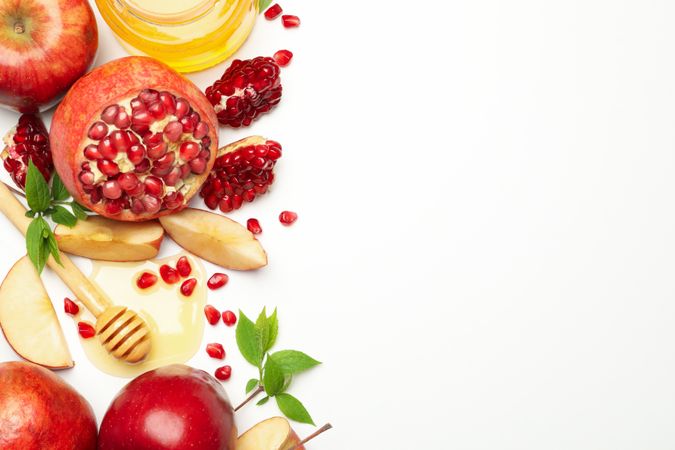 Top view of pomegranate with apples, honey and mint leaves on side with copy space