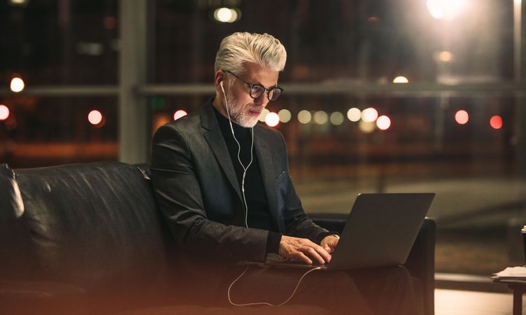 Man in business clothes using laptop computer in office lobby