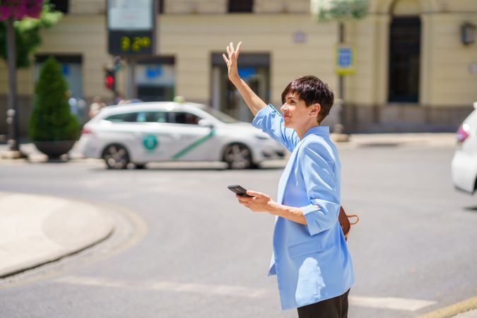 Woman in blue blazer hailing taxi