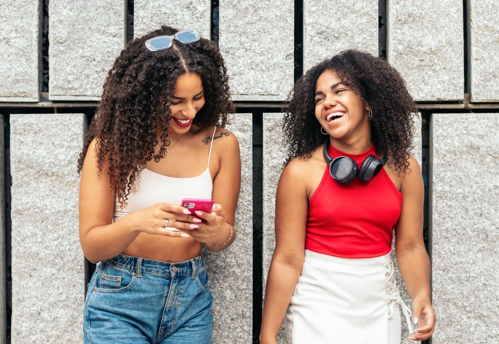Young people online: female friends using smartphone in the city