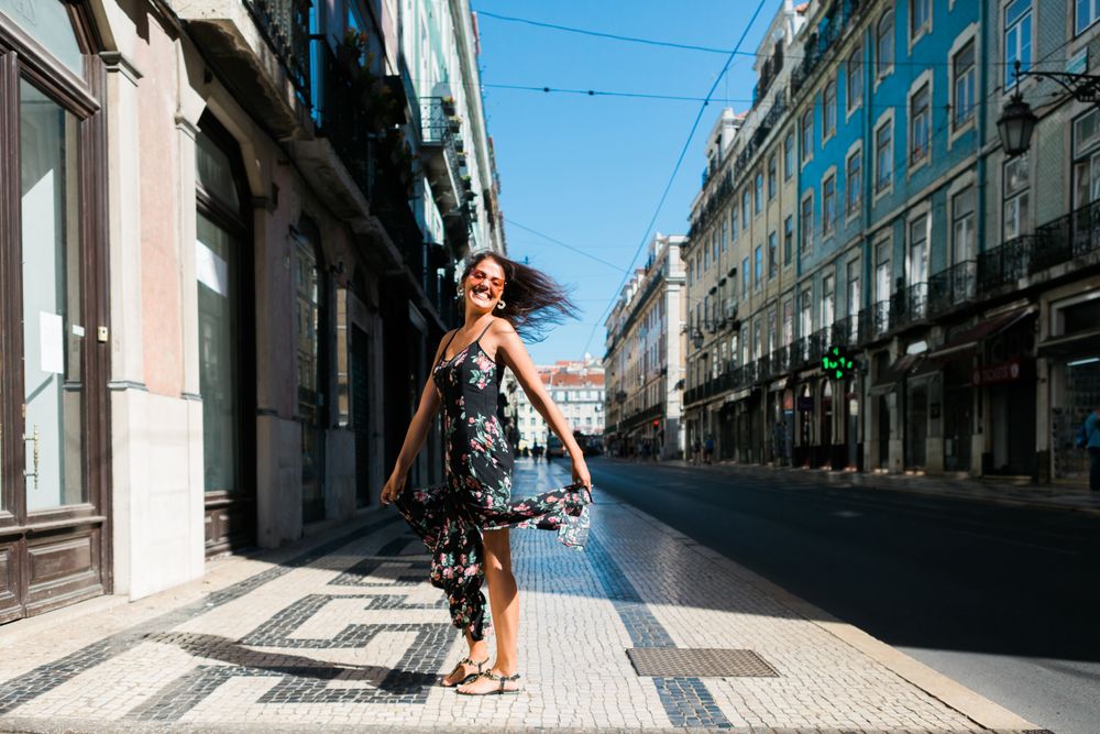 Carefree woman in sundress spinning on street
