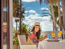 Positive woman having breakfast on hotel terrace