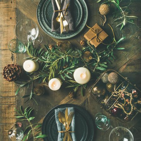Festival holiday table setting on wooden table, with gold ornaments and branches, square crop