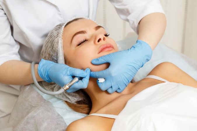 Woman having facial beauty treatment with machine on her jawline