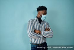 Portrait of a Black man in face mask blue striped shirt with his arms crossed looking away 5p97O4
