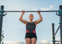 woman athlete doing pull ups on a bar outdoors, calisthenics