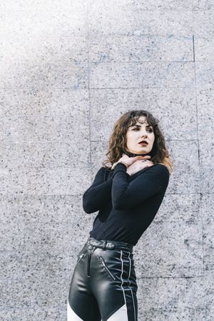 Trendy woman chocking herself near wall