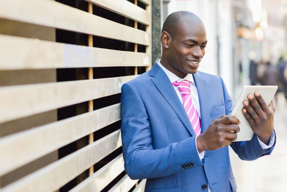 Happy male standing with a digital tablet on street