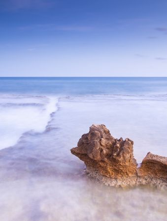 Amazing stones on shore near water and blue sky