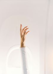 Person in white sweater raising hand up in plane