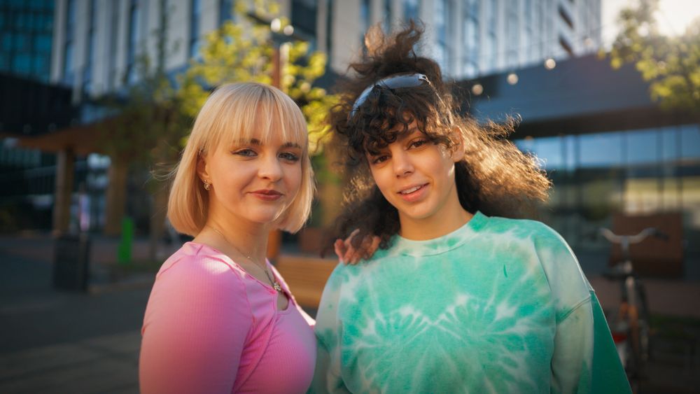 Vibrant Outdoor Scene Capturing Two Young Women Smiling And Enjoying A Sunny Day