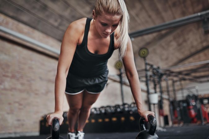 Blonde woman doing planks with kettle bells