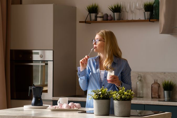 Woman tasting yogurt in sunlit kitchen