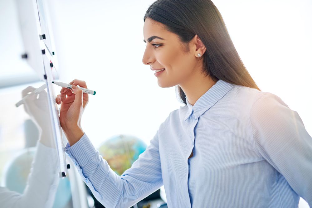 Side view of brunette woman writing on board for work