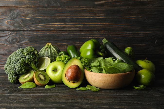 Green vegetables and fruits on wooden background