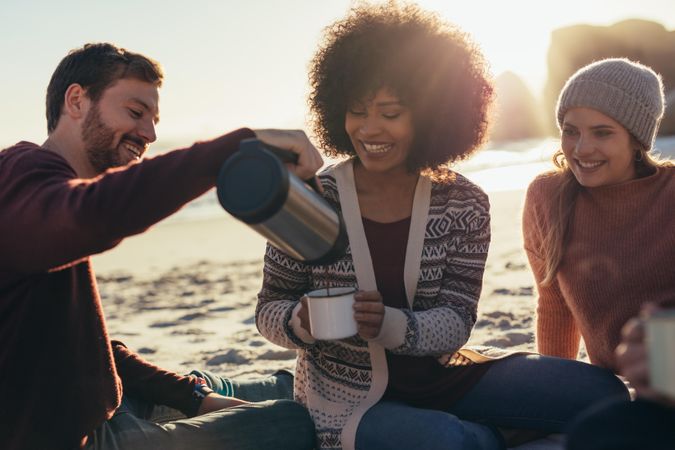 Man pouring coffee in woman's cup at beach