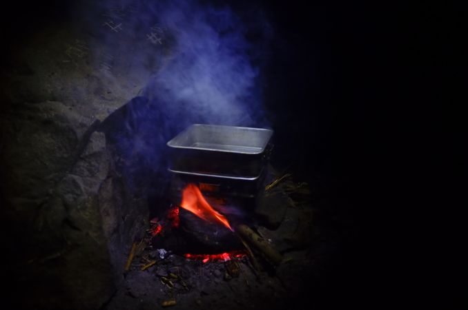 Water on square pan over campfire