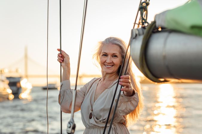 Attractive mature woman posing while standing on a sailboat
