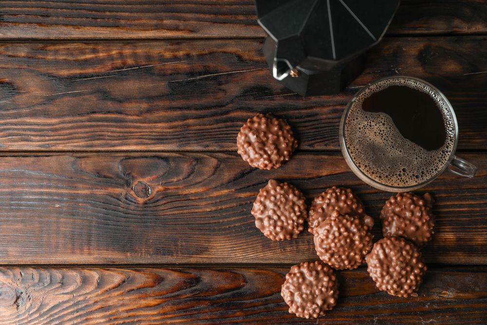 Chocolate cookies and cup of coffee on wooden table, space for text