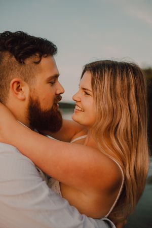 Loving man carrying happy woman on hands on shore