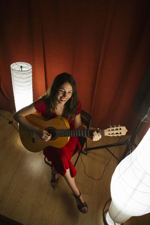 Woman singing and playing guitar on stage in lamplight