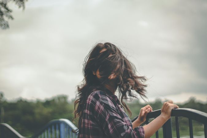 Woman standing on bridge with her hair on her face