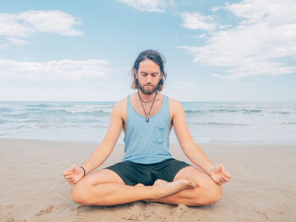 Man training yoga on beach