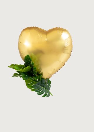 Heart balloon golden with green tropic leaves as decoration