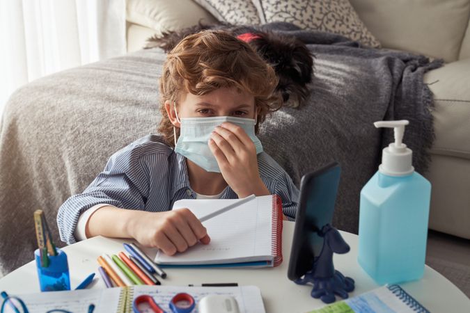 Boy in medical mask doing homework