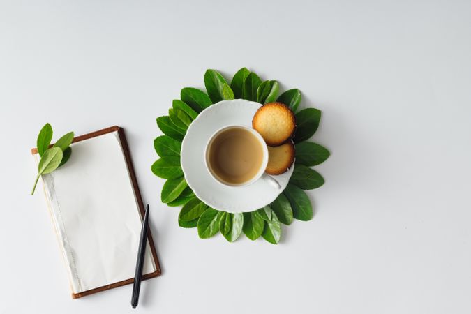 Morning coffee and green leaves in flower shape on light background