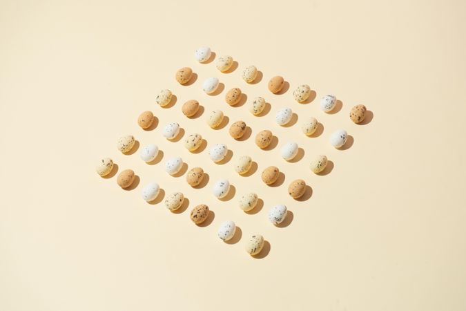 Speckled eggs  in rows on pastel yellow background
