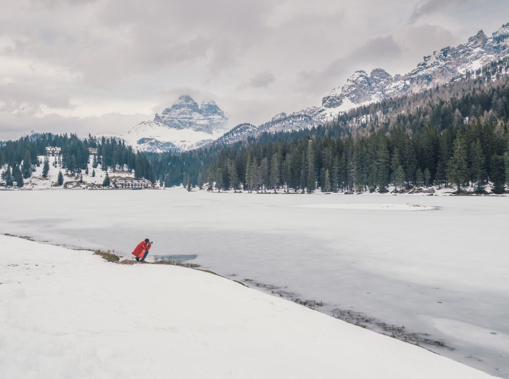 Unrecognizable person standing in snow surrounded by forest and mountains