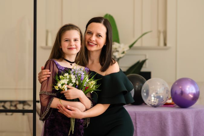 Girl and woman hugging and smiling at birthday party.