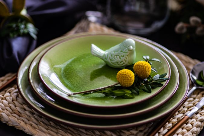 Elegant green plates on placemat for spring themed table with bird ornament