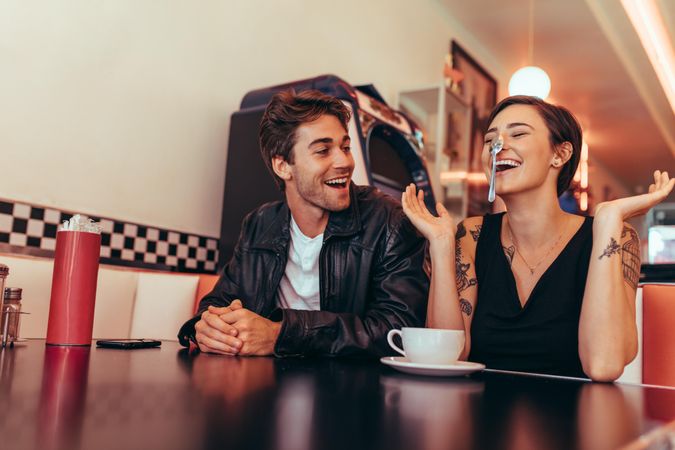 Couple having fun sitting at a restaurant with a coffee cup on the table