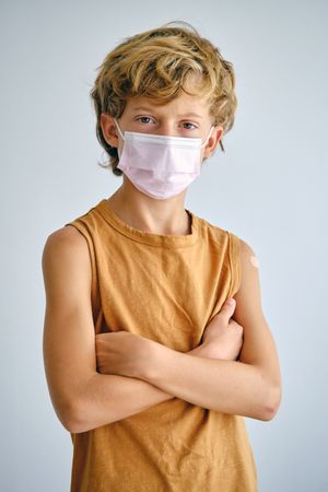Confident boy in medical mask with crossed arms