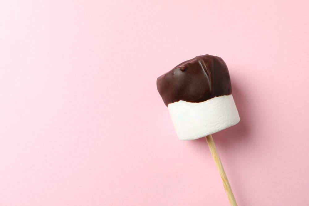 Marshmallow in chocolate on pink background. Sweet food