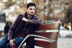 Portrait of man sitting on park bench deep in though