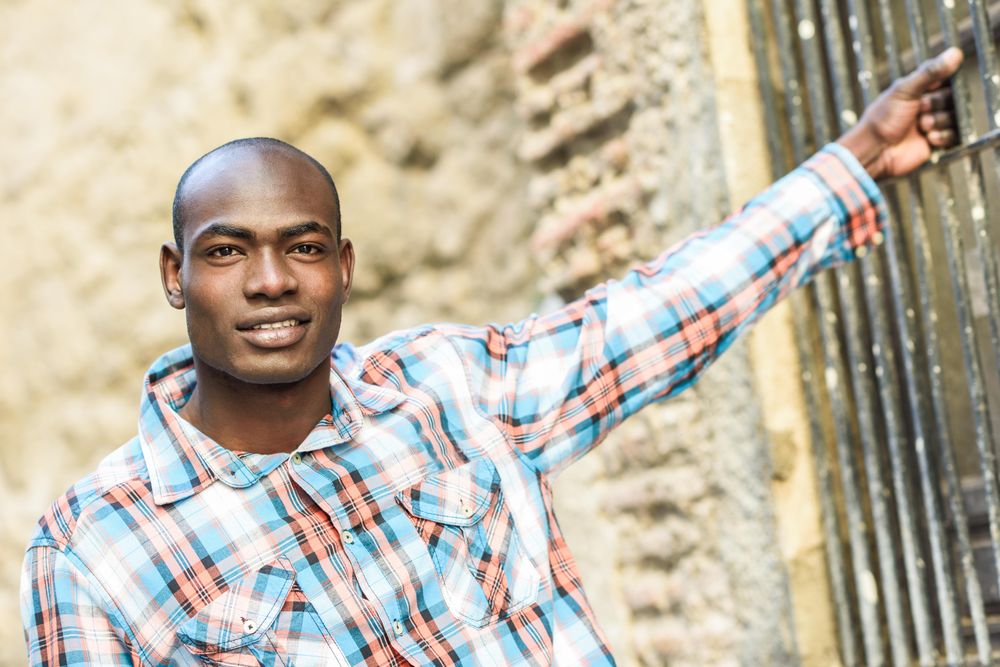 Happy male in plaid shirt with arm holding onto window bars